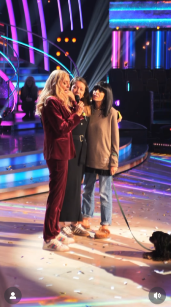 Three women and a dog on a stage with colorful lighting.