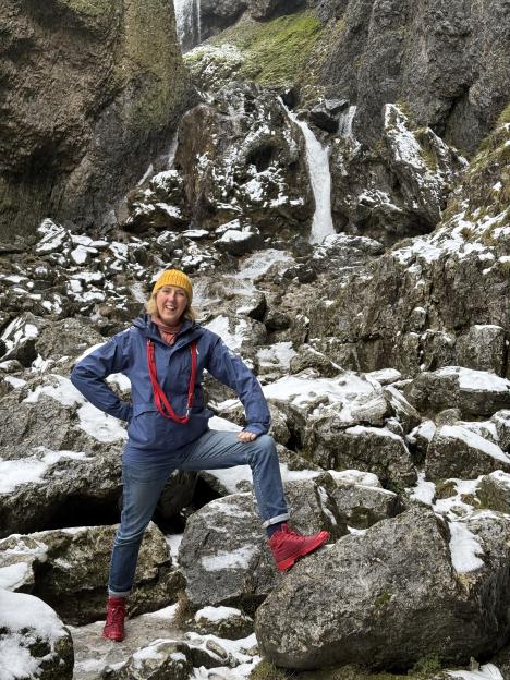 Tracey Davies hiking in snowy Yorkshire with a waterfall in the background.