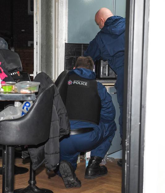 Two Greater Manchester Police officers searching a home for drugs.