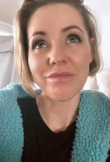 Woman with blonde hair and a blue fuzzy sweater looking upwards.