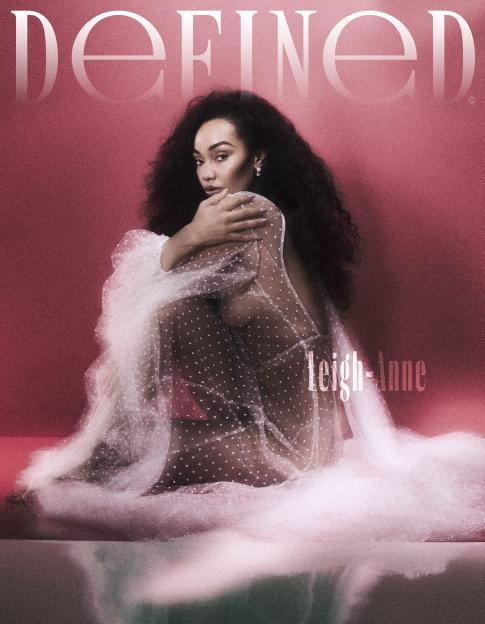 Leigh-Anne Pinnock wearing a sheer, polka-dotted white dress in a sitting pose, against a red and pink gradient background.