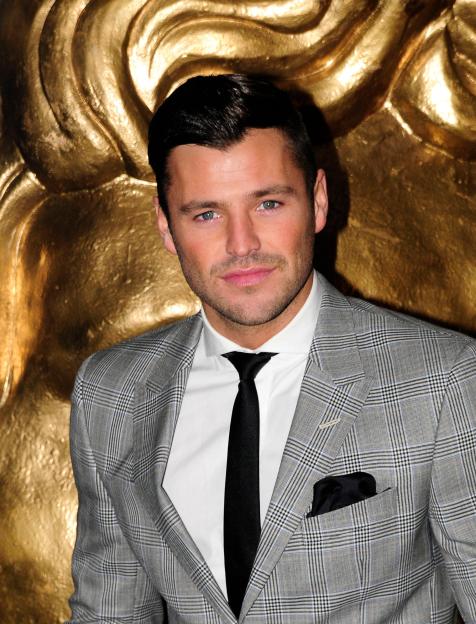 Mark Wright, dressed in a blue jacket with purple trim, looking at a woman with his mouth slightly open.