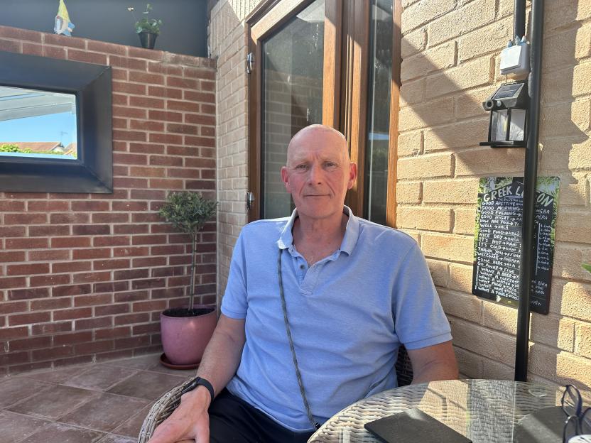 Dog handler PC Neil Simpson sitting in a chair, posing for a photo.