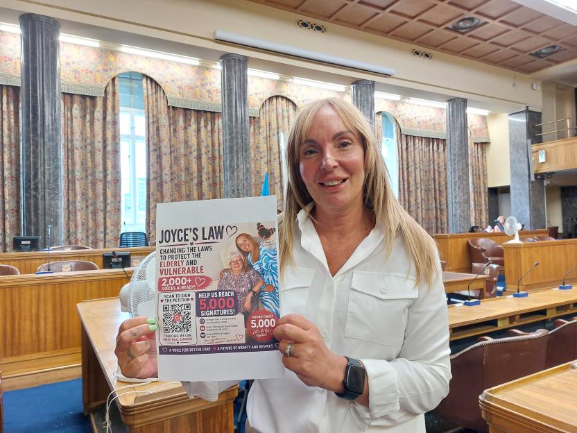 Justine Morrison holding a petition for "Joyce's Law" to protect the elderly and vulnerable.