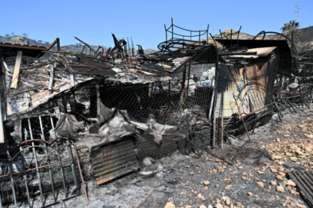 The charred remains of a building after a fire, with debris and ash scattered around.