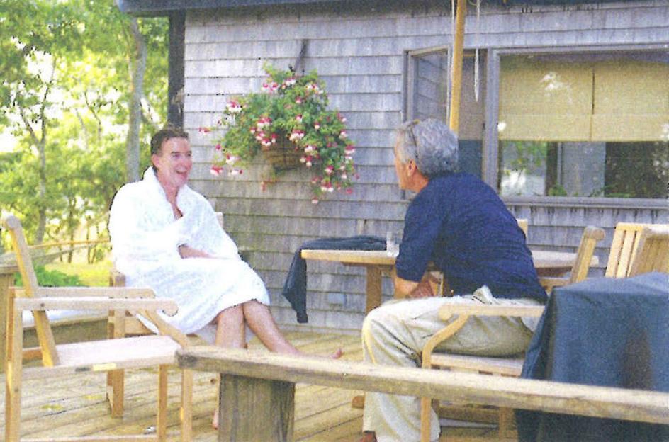 Peter Mandelson in a white robe talking with Jeffrey Epstein on a deck.