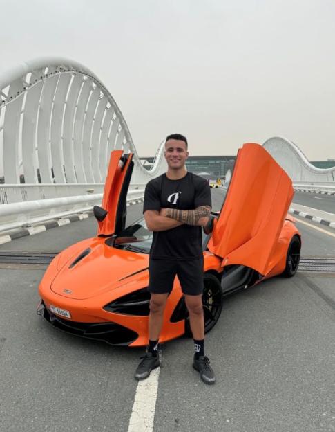 HSTikkyTokky standing in front of his orange McLaren supercar in Dubai.