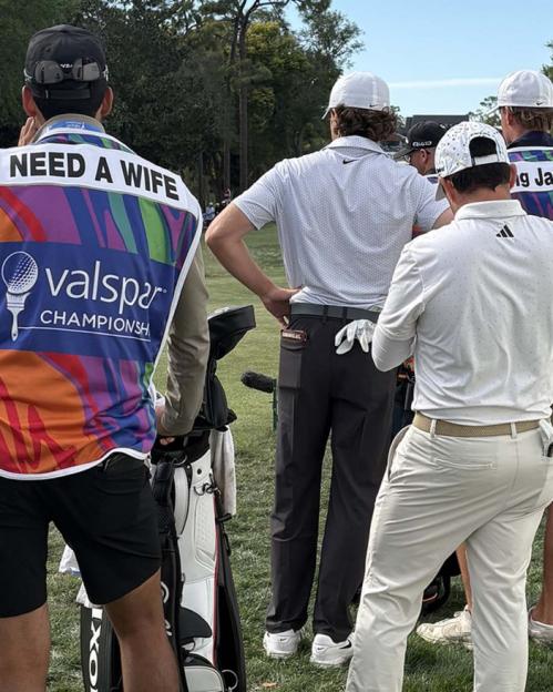 A caddie at the Valspar Championship golf tournament wears a vest that says "NEED A WIFE."