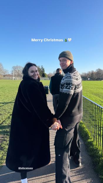 Adam Peaty and Holly Ramsay holding hands, looking back at the camera.