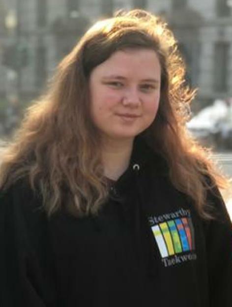 Leah Croucher wearing a black hoodie with a colorful logo.