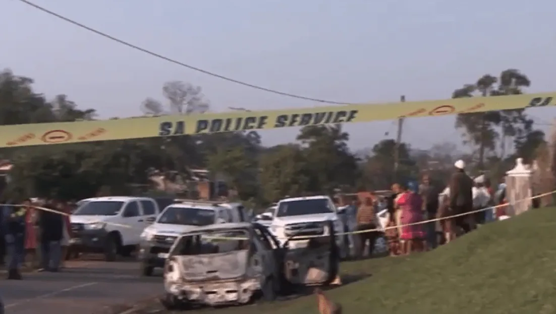 Yellow "SA Police Service" tape cordons off an area with a burned-out car and people gathered.