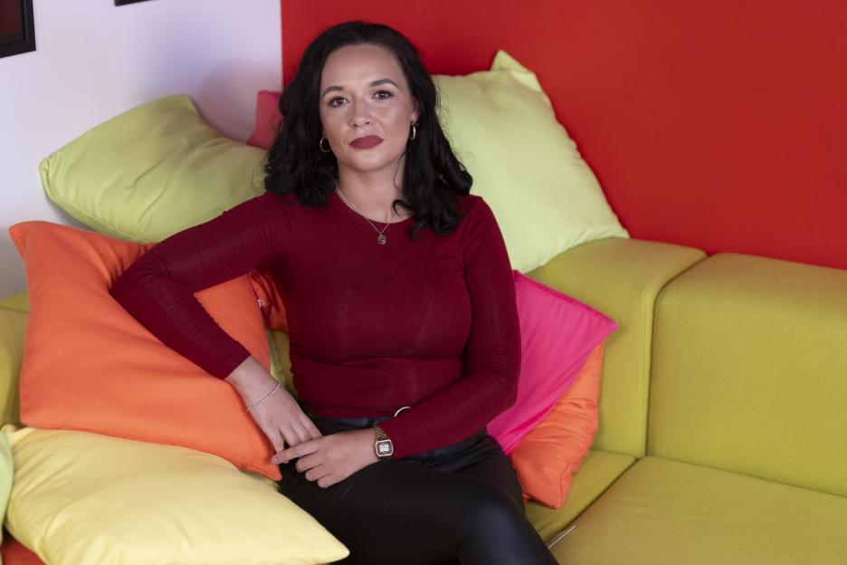 Charlotte Chilton, founder of Sun Club, sitting on a colorful couch.