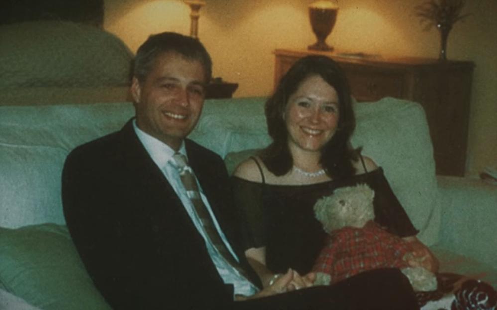 A smiling Diana and Robin Garbutt sitting on a couch.