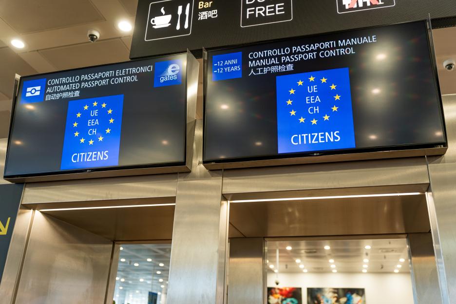 Digital screens at passport control in Venice Airport show information about the EU's Entry/Exit System.