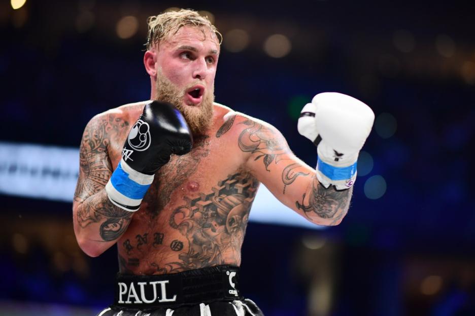 Jake Paul in boxing stance, wearing one black glove and one white glove.