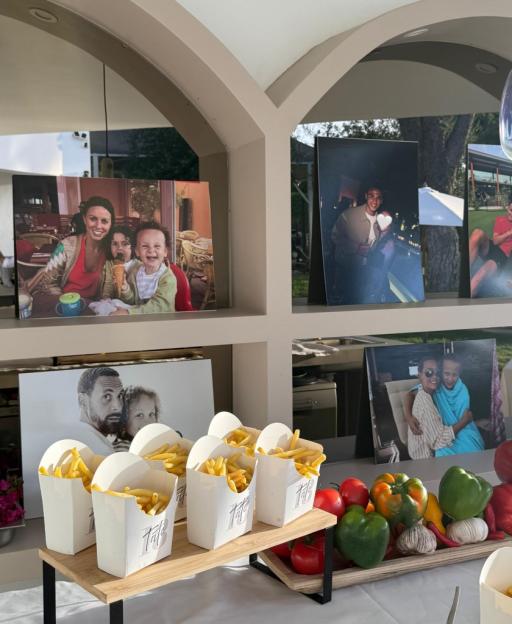 Display of family photos, boxes of French fries, and fresh vegetables on a white tablecloth.