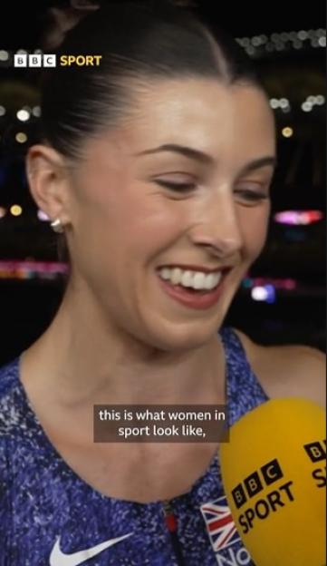 A smiling female athlete wearing a blue and white sports top with a BBC Sport microphone in front of her.