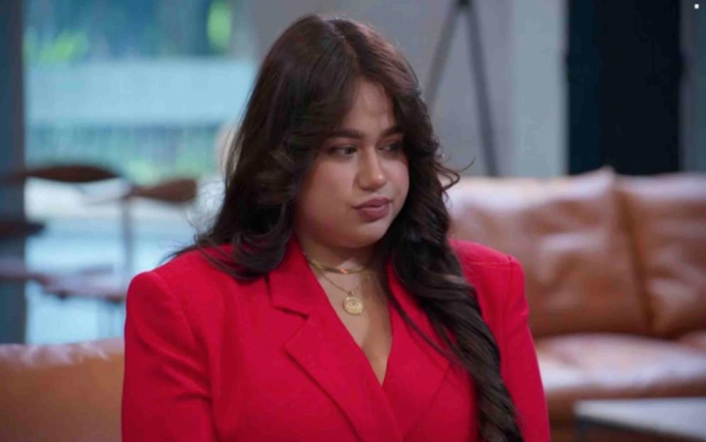 Karishma Vijay from The Apprentice wearing a red blazer and a gold necklace.