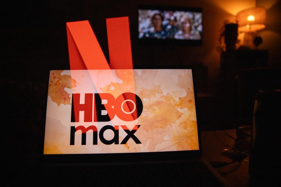Double exposure of the Netflix logo and HBO Max logo on a television screen.
