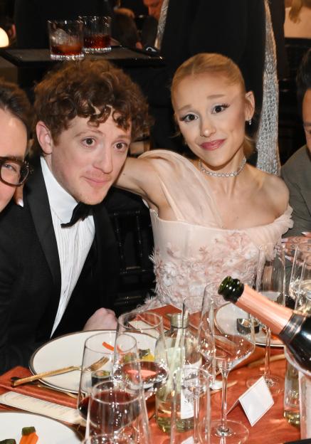 Ethan Slater and Ariana Grande seated at a table during the 31st Screen Actors Guild Awards.