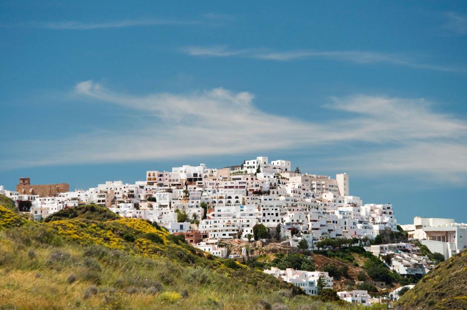 Mojácar Village, Almería, Andalusia, Spain, with white buildings on a hilltop under a blue sky with wispy clouds.