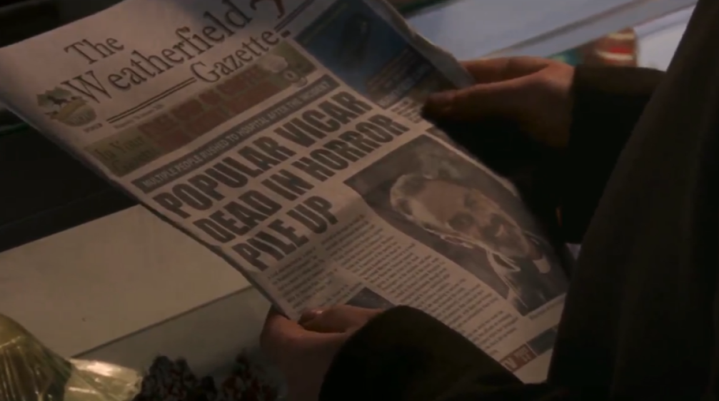 A person holding a newspaper with the headline "POPULAR VICAR DEAD IN HORROR PILE UP".