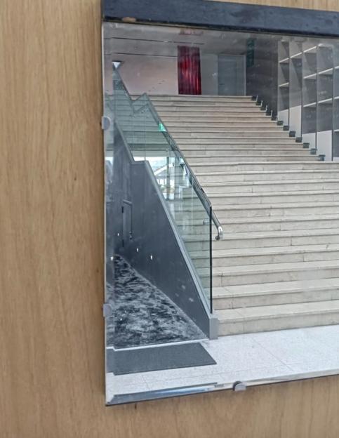 The artwork "Inverted Syntax – 16" by Chen Sung-chih after being cleaned, showing a clear mirror reflecting a modern stairway and a red curtain.