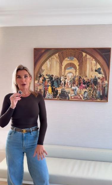 Billie Faiers stands in front of a large painting with many characters.