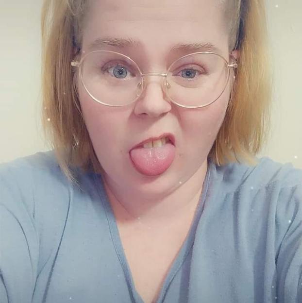 A woman with blonde hair and glasses sticking her tongue out.