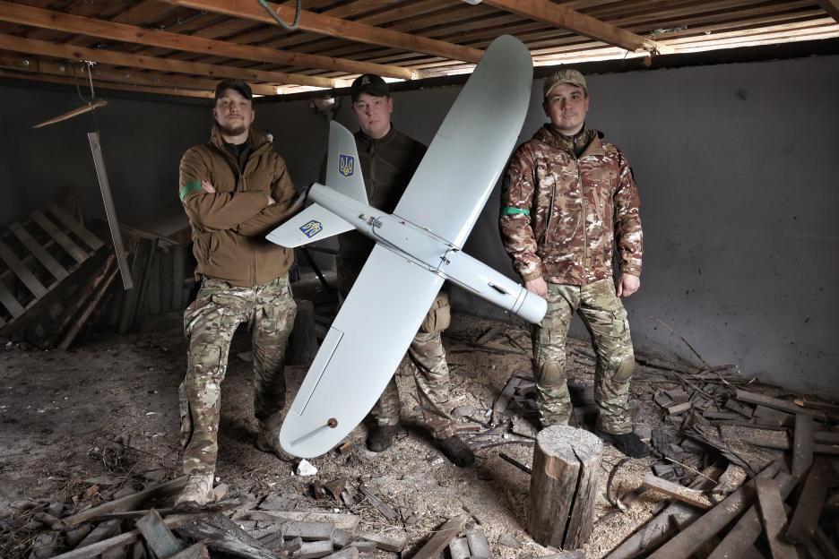 Three Ukrainian reconnaissance police officers pose with a Leleka drone.