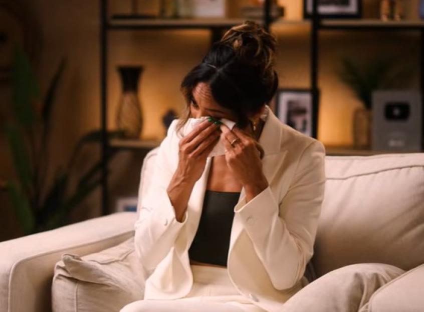 Karen Hauer crying and wiping tears with a tissue, wearing a white blazer and black top.