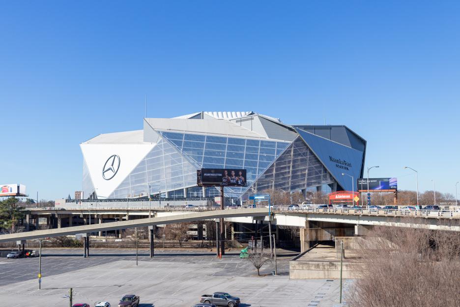 Mercedes-Benz Stadium in Atlanta, Georgia, with highway overpasses and empty parking lots in the foreground.