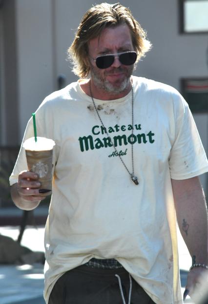Elijah Blue Allman with long hair, beard, sunglasses, a Château Marmont T-shirt, and long fingernails holding a Starbucks drink.