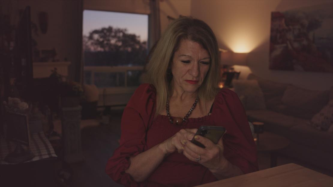 Annette looks down at her phone with a concerned expression.