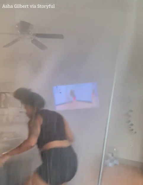A woman reacts as a pole-dancing practice causes a ceiling sprinkler to activate, filling the room with water.