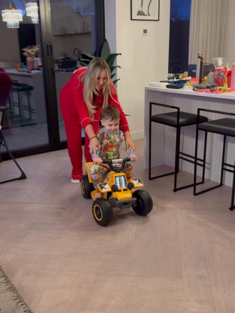 Holly Hagan helps her son ride a yellow toy quad bike.