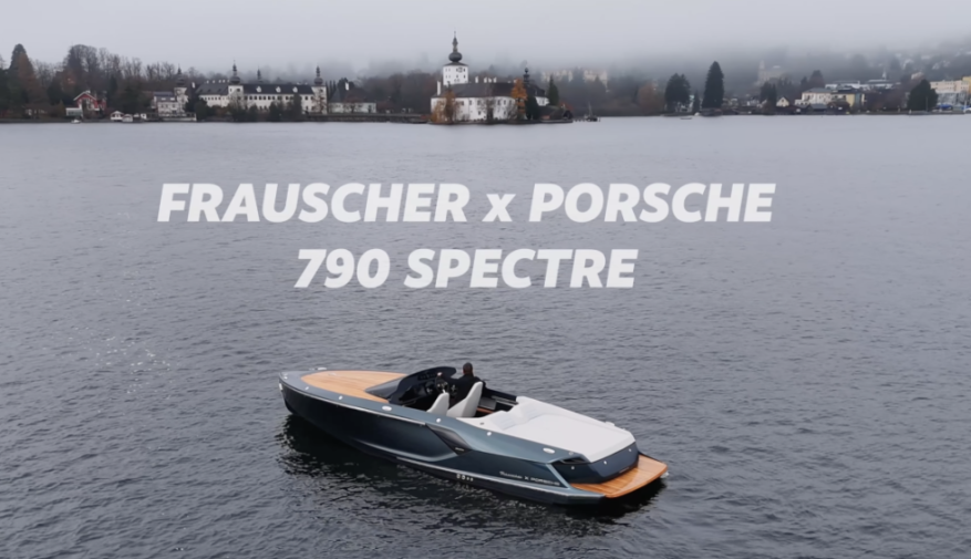 A Frauscher x Porsche 790 Spectre boat on a lake with a town in the background.