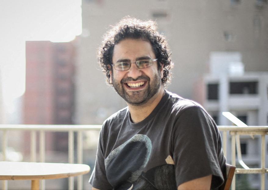 Activist Alaa Abd el-Fattah smiles while sitting outdoors.