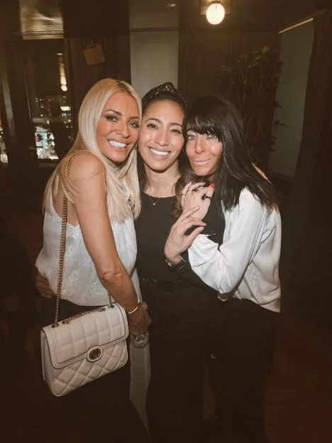 Tess Daly, Karen Hauer, and Claudia Winkleman posing together.