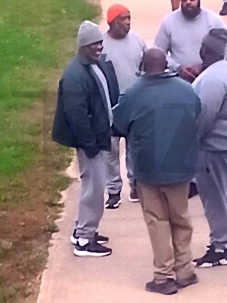 Diddy smiling and chatting with other inmates in a prison yard.