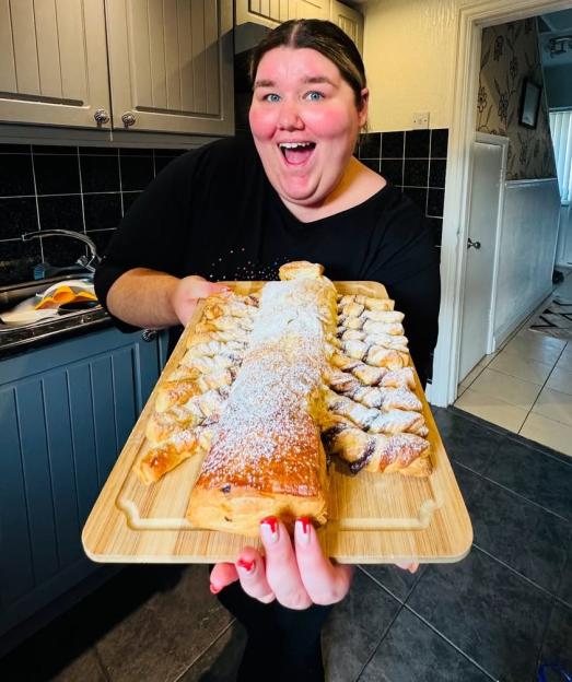 Becky Jones holding a pastry on a wooden board.