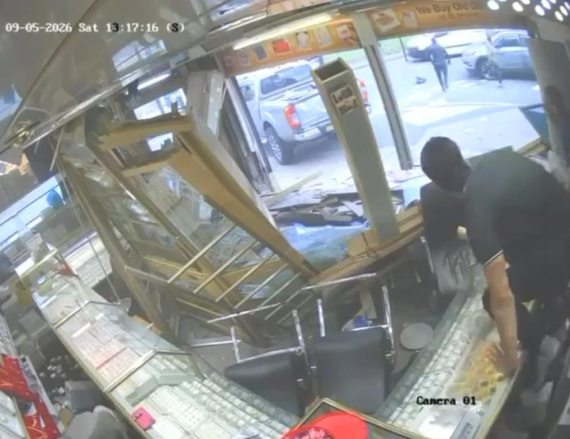 CCTV footage shows a masked thief looting gold from a smashed jewelry store display case.