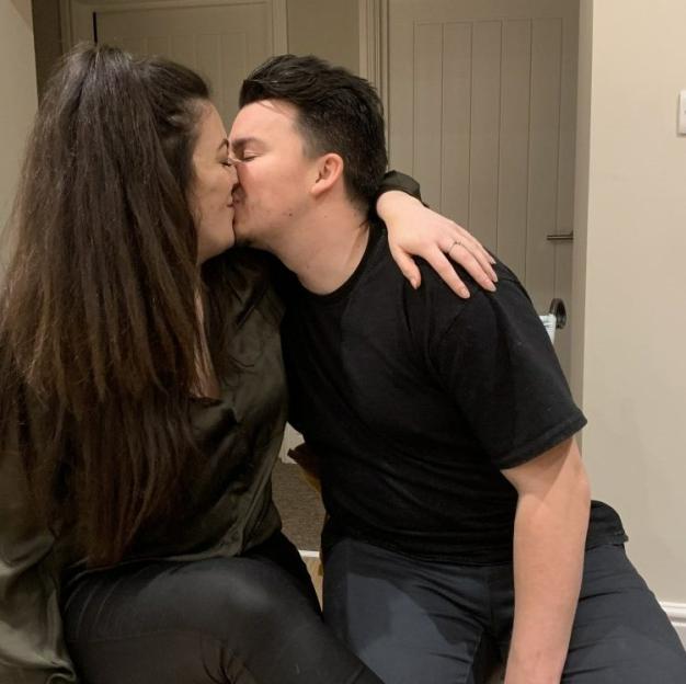 A man and a woman kissing, with the woman's arm around the man's neck.