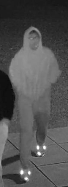 CCTV image of a man in a hooded sweatshirt and reflective shoes.