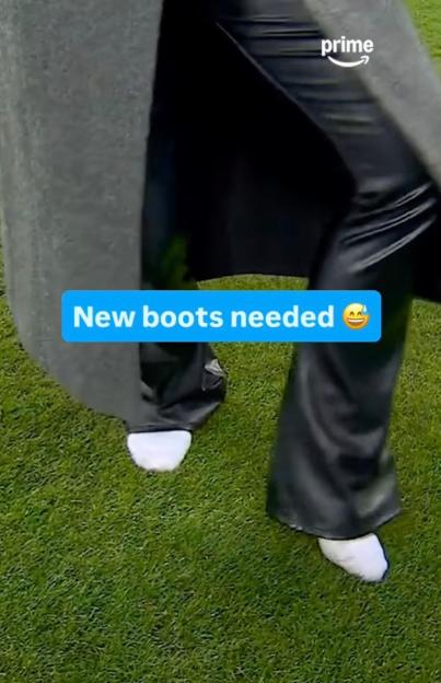 A person's feet in white shoes and black pants on green grass.