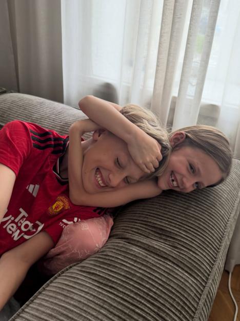 Two children laughing while embracing on a couch.