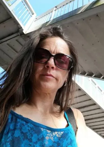 Portrait of Joanne Sheen wearing sunglasses and a blue lace top.