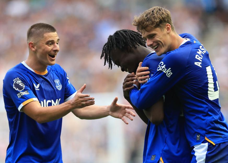 Three Everton players in blue jerseys celebrating a goal.
