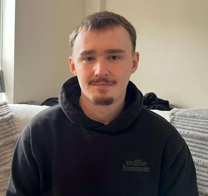 A young man with a mustache and goatee sitting on a couch.