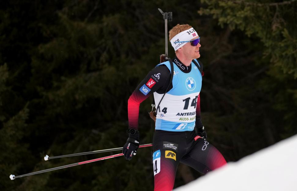 Norwegian biathlete Erlend Bjoentegaard (bib 14) skiing in a red, black, and blue uniform.